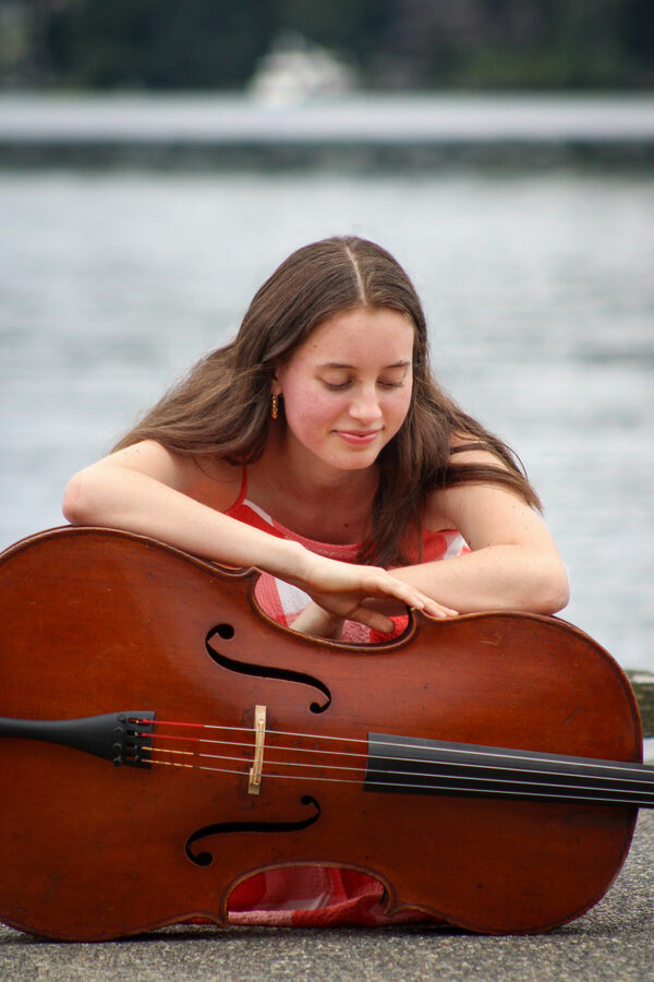 Martha resting on her cello by the water