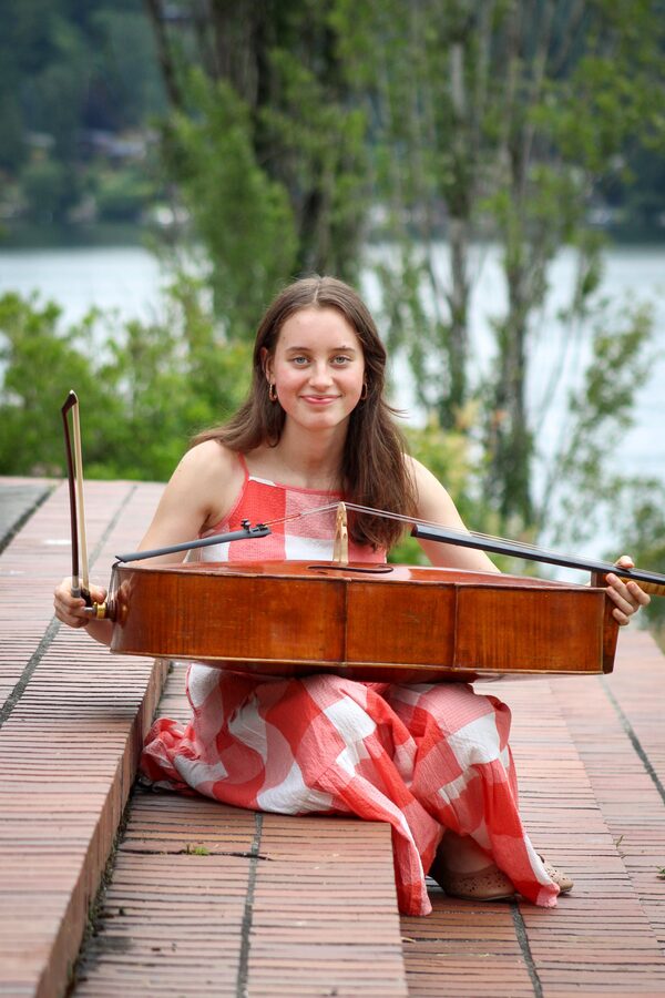 Martha seated with her cello on a boardwalk