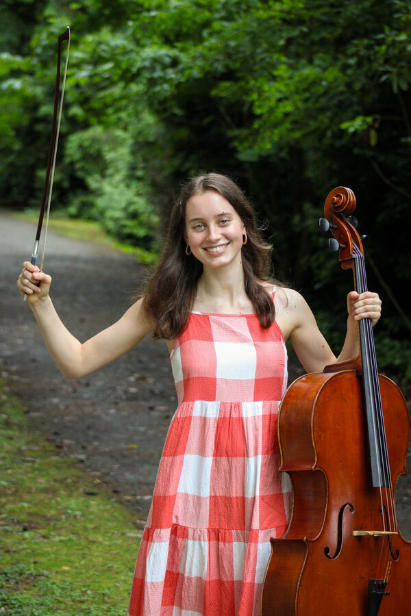 Martha standing outdoors with her cello and bow